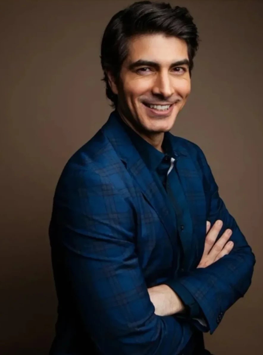 Brandon Routh in a dark blue checked jacket, arms folded.